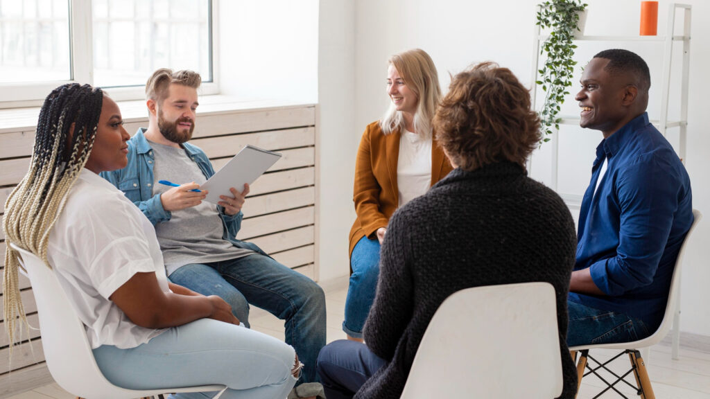 Groupe d’adultes assis en cercle, en pleine discussion dans un cadre communautaire