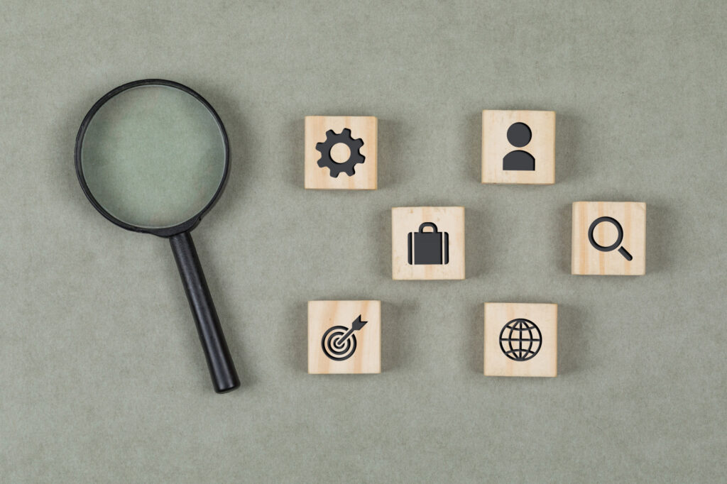 Cubes en bois et loupe posés sur un fond gris, symbolisant l’analyse et les ressources pratiques